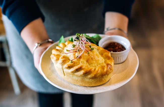 Close up of a waitress holding a pie.