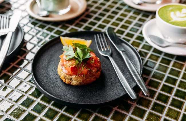 Housemade crumpet with salmon and herbs, and a slice of lemon on the side