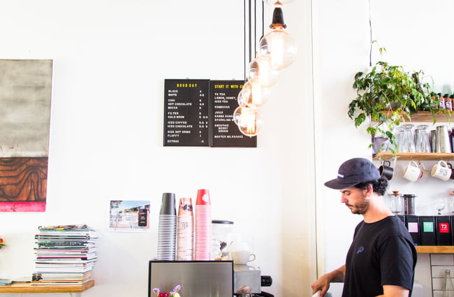 Making coffee under the blackboard menu.