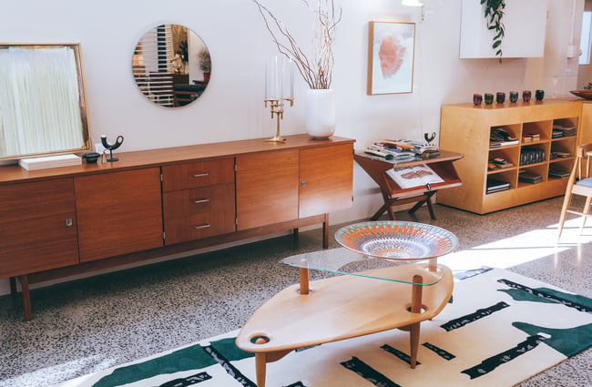 A display set of a lounge with a coffee table on a fluffy white and blue rug.