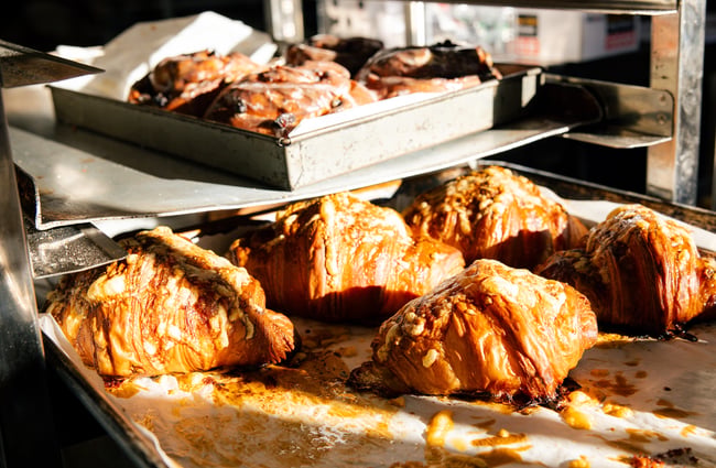Sunlight gracing freshly baked trays of cinnamon buns and croissants at Gourmet Gannet.