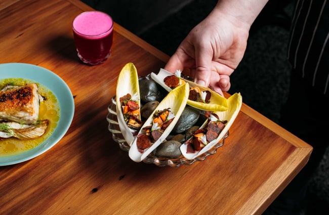 A dish of food being placed on a table by a chef.