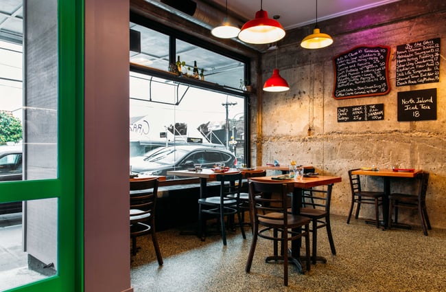 The large window at the front of the wine bar with seating inside the restaurant.