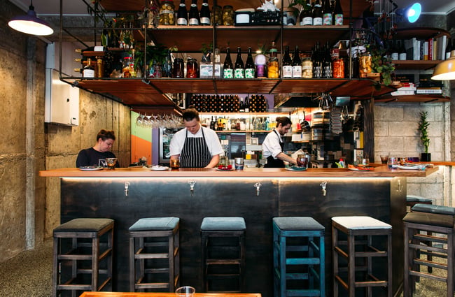 Three staff members working behind a well stocked counter and bar.