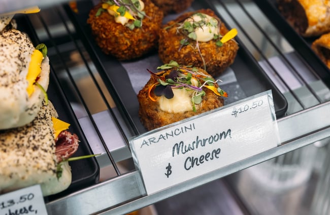 Close up of arancini on a tray inside a glass cabinet.