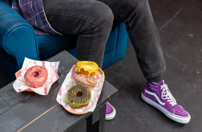 Three donuts are sitting next to a customer at a table at Grumpys.
