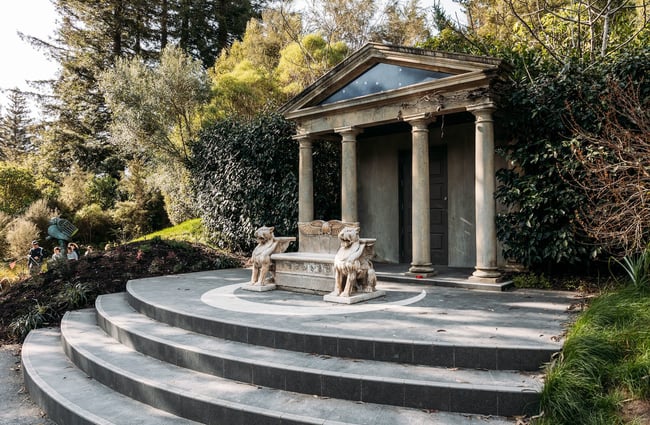 Round steps lead up to a marble statue in front of a portico.