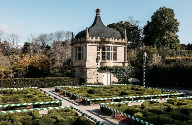 Box hedges in geometric patterns and a pointed roof tower in the Tudor Garden.