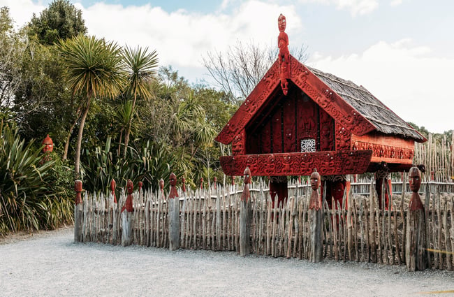 Traditional Māori storehouse surrounded by pointed wooden spike fence.