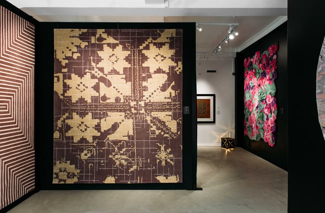 Large rugs on display against black walls.