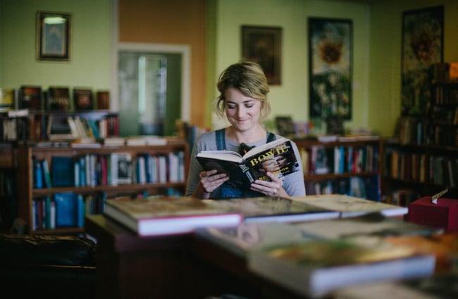A woman reading a book about David Bowie.