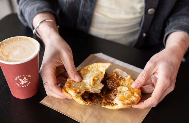 Customer pulling apart a pie with a coffee sitting alongside it on the tables at Harris Farms Butchery, Bakery & Café.