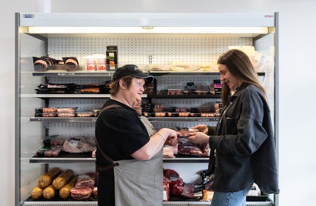 Staff member helping a customer in front of the butchery section at Harris Farms Butchery, Bakery & Café.
