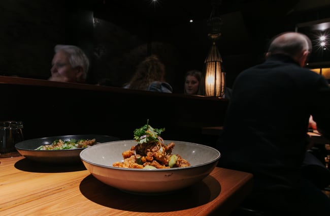 Bowl of fried chicken with diners in the background.
