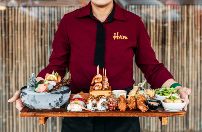 Wait staff holding a large platter of different food dishes at HARU.