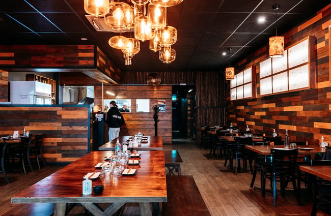 Long dining table with pendant lights above in the dining room at HARU.