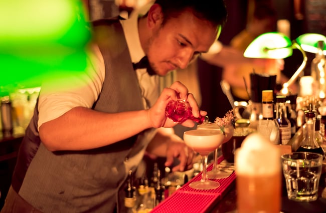 Pouring drinks behind bar.