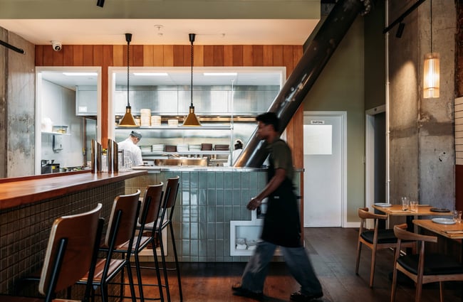 Staff member crossing in front of the kitchen at Hei.