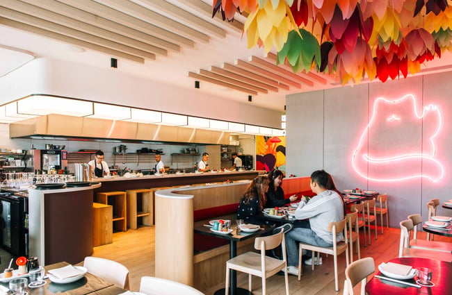 Chefs in kitchen with dining room in the foreground at Hello Beasty, Auckland Viaduct Harbour.