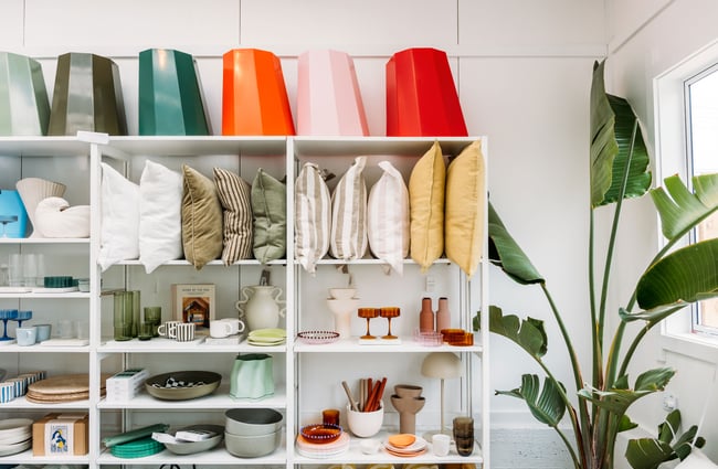 Brightly coloured cushions and homewares on shelves.