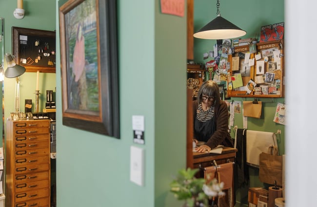 Woman writing behind desk at Henry Trading in Lyttelton