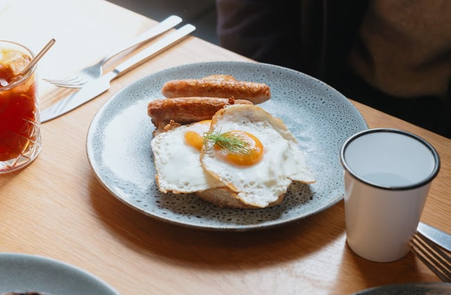 A plate of eggs and sausages on toast on the table.