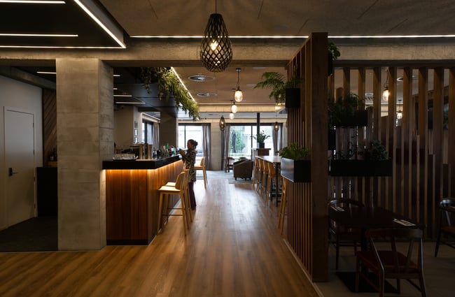 A large restaurant area with a staff member standing at the bar.