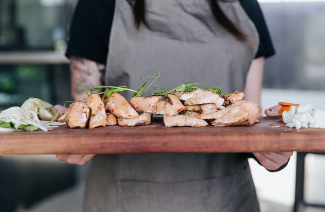 A chef holding a plate of salmon.