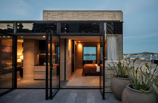 A view of inside a hotel room from on top of a building in Auckland at dusk.