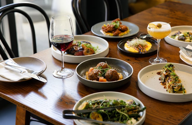 Plates of food and glasses of wine on a table.