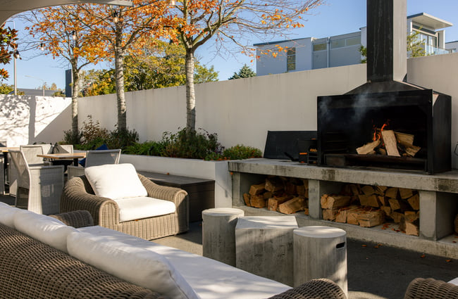 White seating next to an outdoor fireplace on a sunny day.