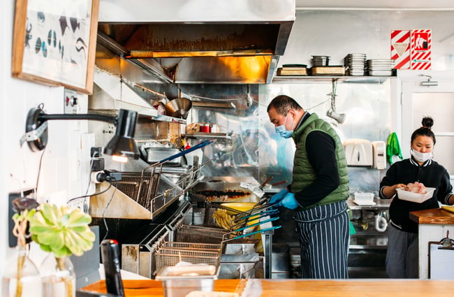 Two staff members working behind the counter wearing face masks at Huckle and Co.
