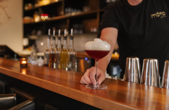 Bartender serving a cocktail at Imōto Lounge Bar.