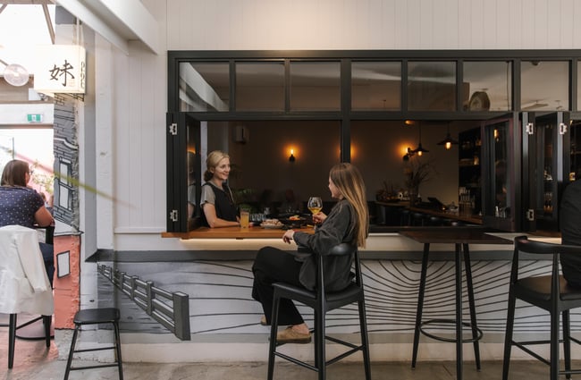 Customers sitting at the bar leaner table at Imōto Lounge Bar.