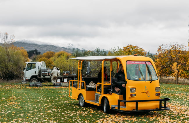 Tour vehicle in the orchard and fruit pickers in the background at Jackson Orchards.