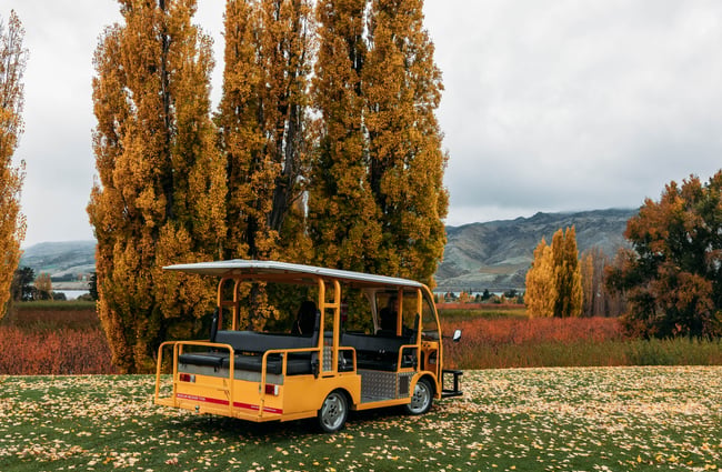 Tour vehicle in the orchard with autumnal foliage in the background at Jackson Orchards.