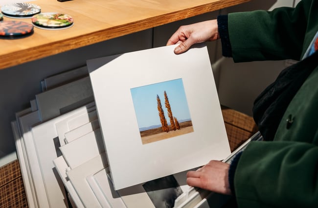 Hands holding a small painting.