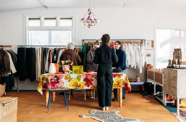 Women standing around inside a retail store chatting.