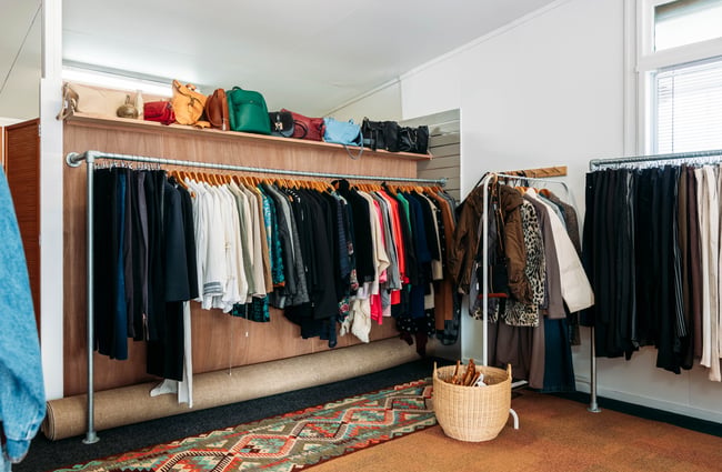 Dark clothes on display on racks inside a clothing store.