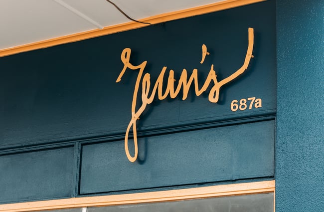 A close up of the 'Jean's' sign at the top of an exterior cafe wall.