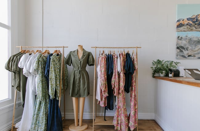 Colourful dresses and jumpsuits on a mannequin and on floating clothes racks.