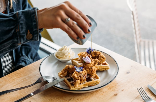 Maple syrup being poured on to waffles in a cafe.
