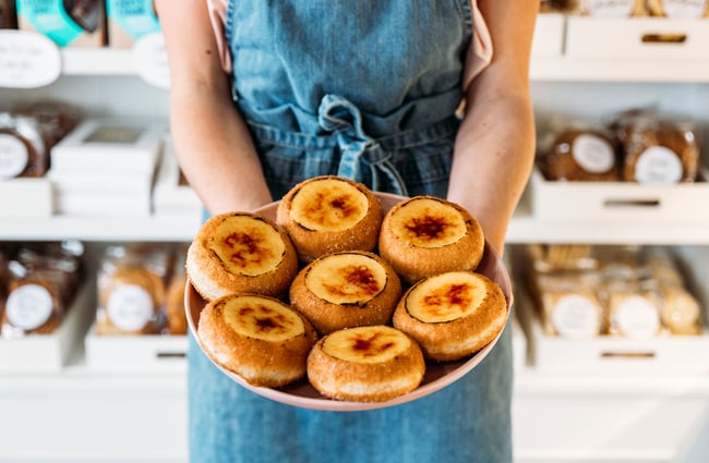 Hands holding a plate of cheesy pastries.