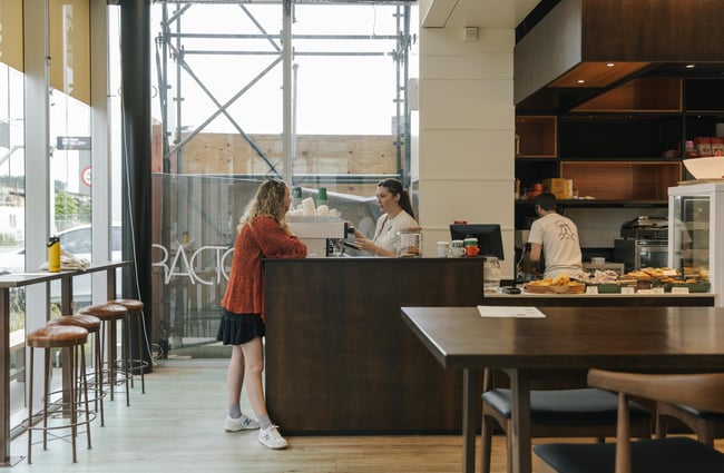 Customer and barista talking by coffee machine at Jolly Deli.