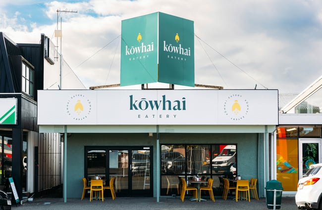 Cafe building exterior with bright green signage for Kōwhai Eatery.
