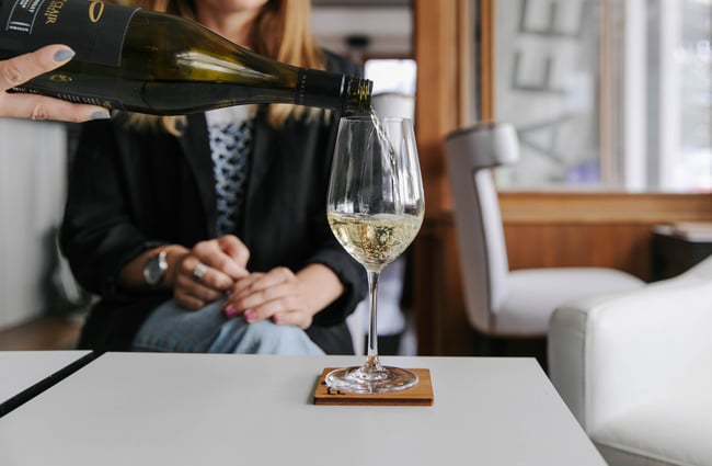 Pouring wine into a glass in lounge area at Kaikōura Boutique Hotel.