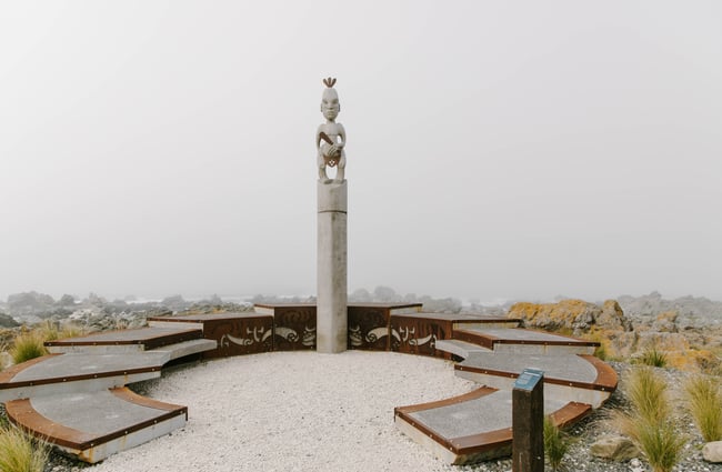 Close up of pouwhenua with seating area beside it.