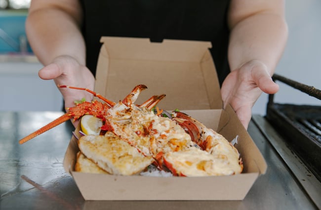 Takeaway box with cooked crayfish dish inside.