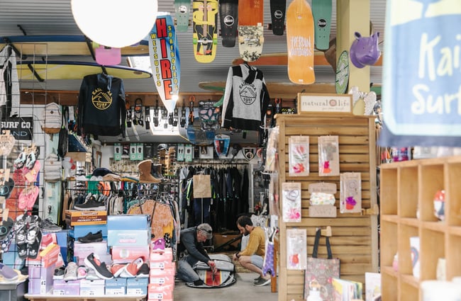 Two men putting fins on a surfboard at Kaikōura Surf Company.
