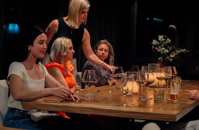 Server pouring wine for guests seated at the table at Kaitahi Lodge.
